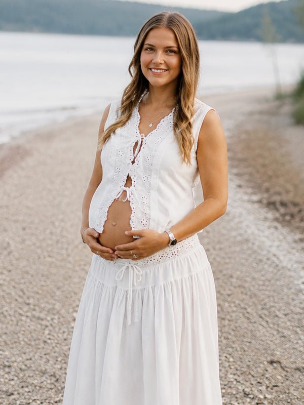 White lace maternity maxi dress with lace-up openwork two-piece design and elegant silhouette, designed for photoshoot.