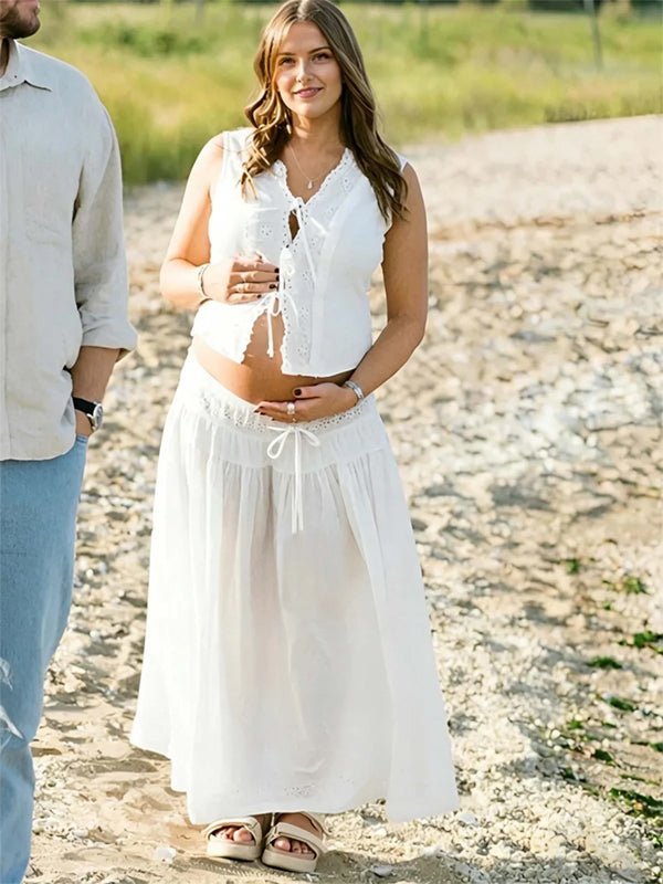 White lace maternity maxi dress with openwork lace detail and lace-up two-piece design.