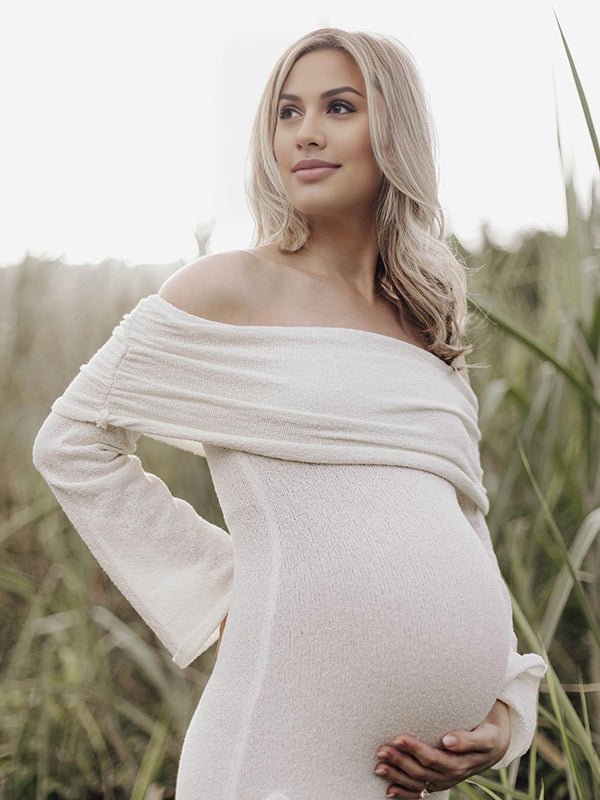 White maternity maxi dress with 3D floral appliqués and bodycon silhouette.